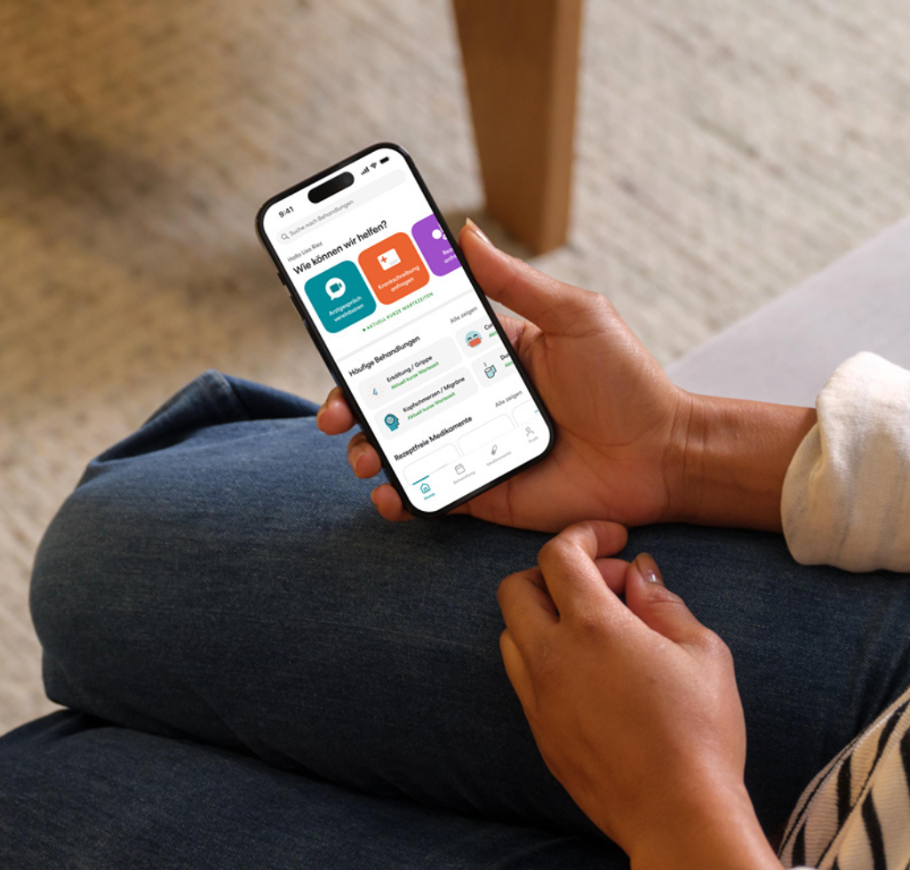 Eine Person hält ein Handy in der Hand worauf die TeleClinic App Startseite zu sehen ist.