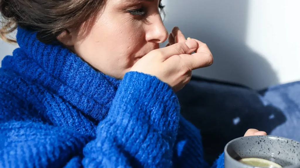 Frau in blauem Pulli trinkt Tee
