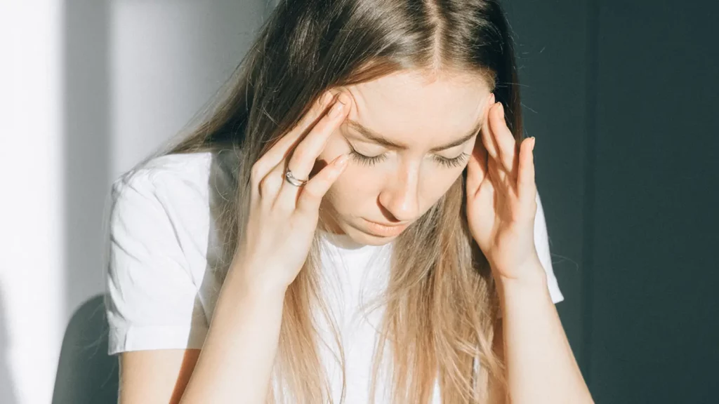 Junge Frau hält sich die Hände am Kopf