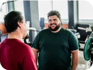 Mann mit Bart, der sich im Fitnessstudio mit einem Freund unterhält.