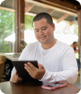 Junger Mann, der mit einem Tablet in einem Café sitzt.