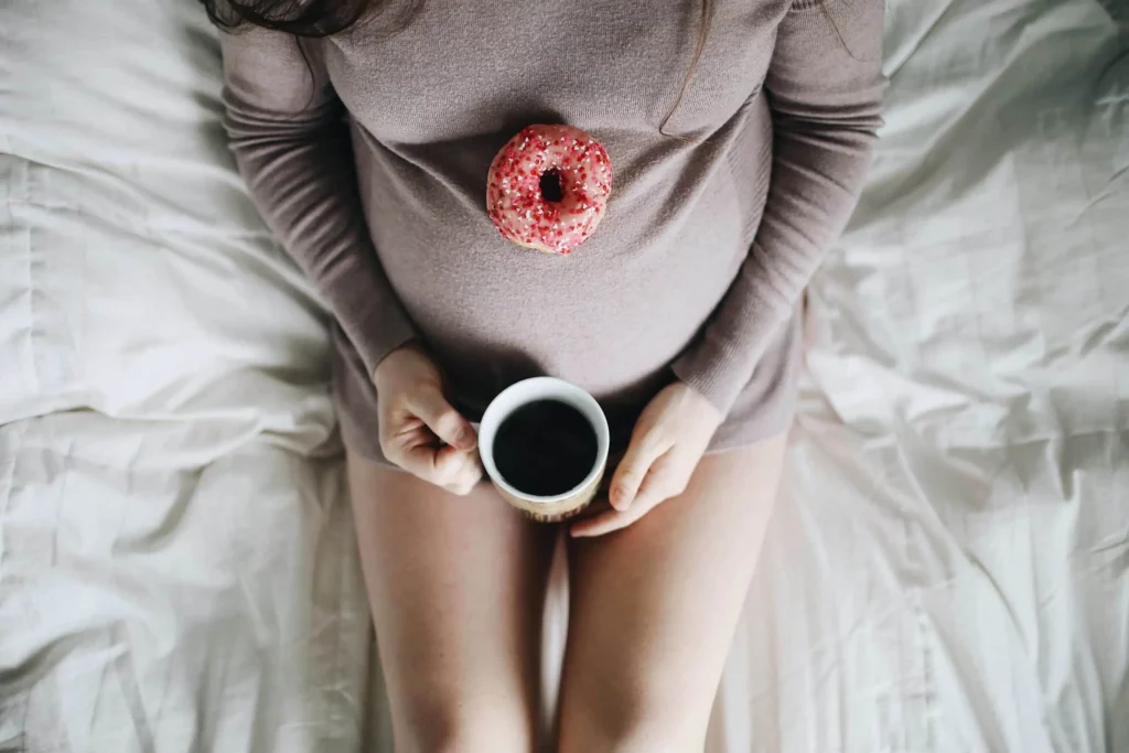 Schwangere Frau mit Kaffee im Bett