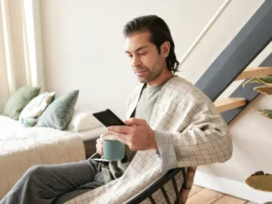 Mann entspannt mit Kaffee und Smartphone, symbolisiert digitale Behandlung von zu Hause.