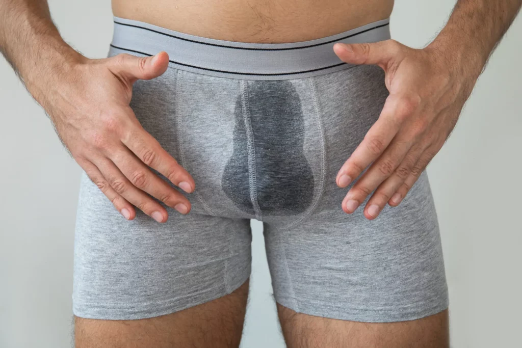 Mann in Unterhose mit nassem Fleck. 